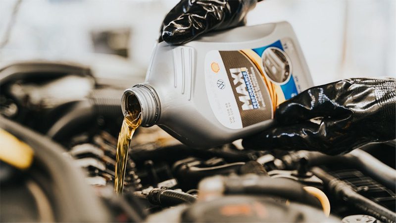 Oil change in progress on a car engine, with fresh oil being poured in.