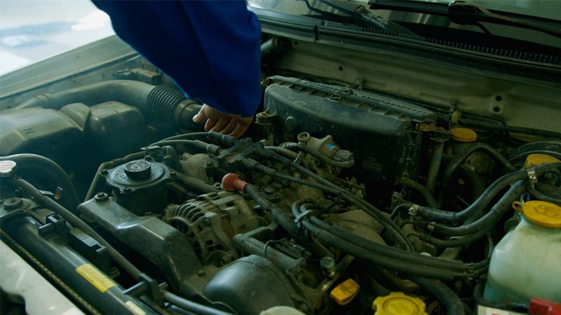 Mechanic working on a car engine, performing maintenance and repairs