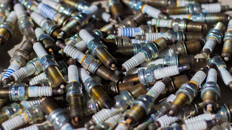 Old, worn-out spark plugs laid out on a surface, prepared for disposal or desertion.