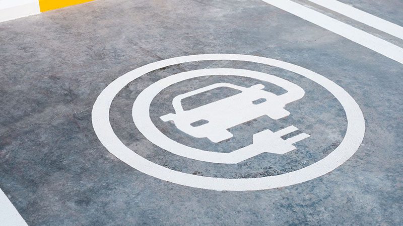 EV car charging sign painted on a parking lot ground, indicating electric vehicle charging zone.