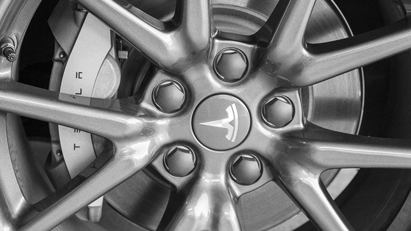 Close-up of a Tesla car wheel featuring the Tesla logo and sleek rim design.