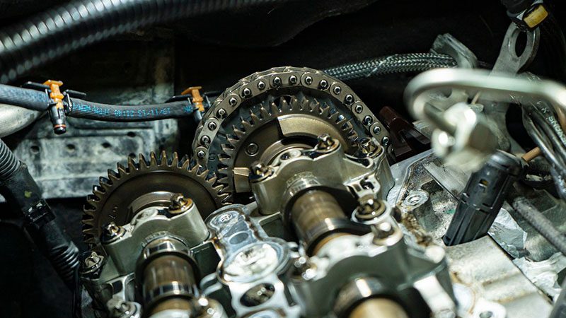 Detailed view of a timing chain inside a car engine, showing metal links and internal drive components.