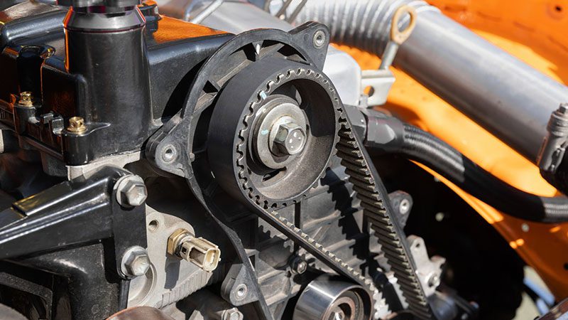 Close-up of a timing belt and camshaft sprocket inside a car engine, highlighting engine timing components.