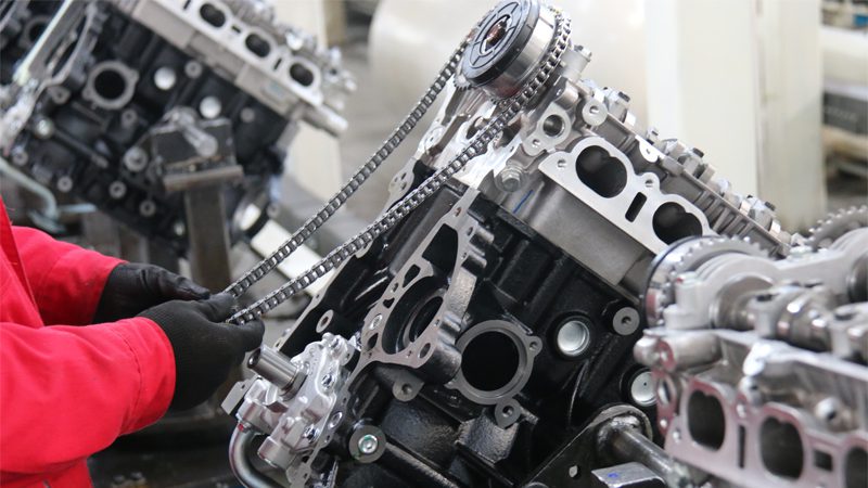 Mechanic installing a timing chain on a newly assembled engine at Nanjing Woda Auto Technology Co., Ltd. production line.