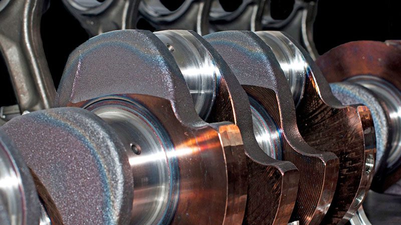 Close-up of a crankshaft with attached piston rods, showcasing engine assembly components
