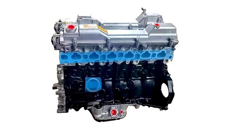 Front view of a bare Toyota 2JZ engine block and head, showing exposed pulleys and accessory mounts.