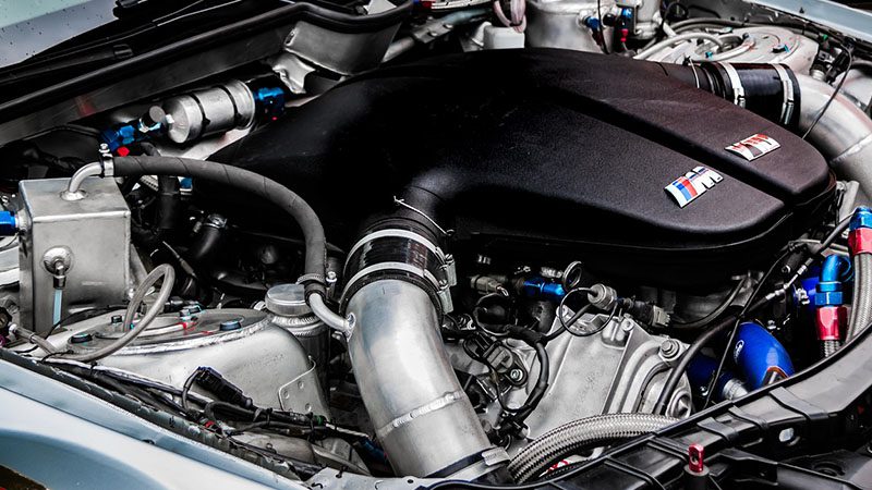 Close-up view of a car engine showcasing key components involved in Variable Valve Timing (VVT).