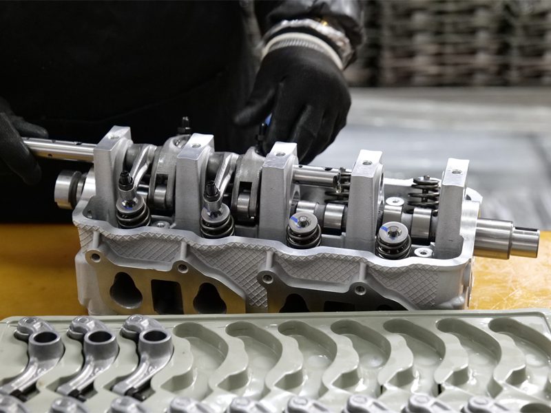 Mecânico instalando cabeçote de cilindro na linha de montagem de motores na fábrica da Woda Auto.