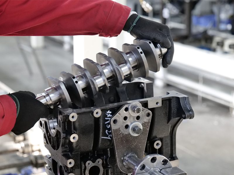 Mechanic placing a crankshaft into an engine block on the auto engine production line at Nanjing Woda Auto Technology Co., Ltd.