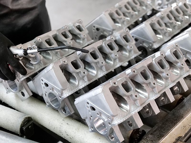 Mechanic cleaning new cylinder heads before engine assembly.