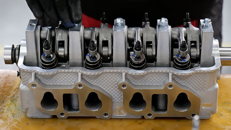 Mechanic assembling a cylinder head in an automotive workshop.