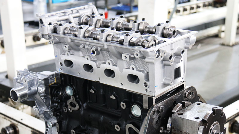 Newly assembled automotive engine with aluminum cylinder head and dark engine block.