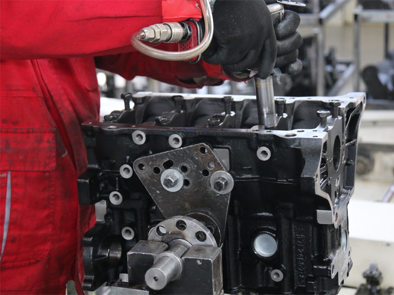 Auto engine manufacturing process, focusing on the careful assembly of engine components for reliability and performance.