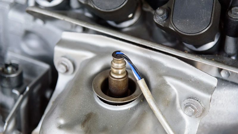 Close-up of oxygen sensor installed in a car engine exhaust system.