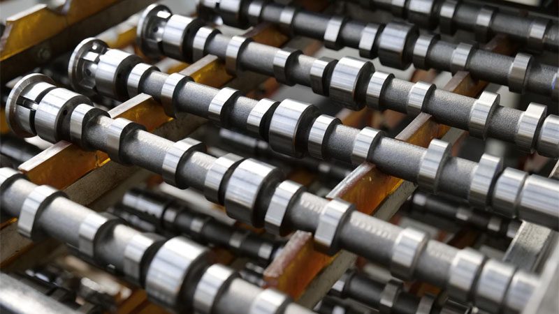 Precision camshafts arranged for quality inspection in automotive parts facility.