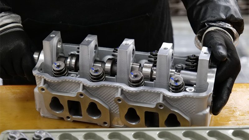 صورة مقربة للميكانيكي الذي يقوم بمحاذاة مكونات رأس الأسطوانة أثناء تجميع المحرك.