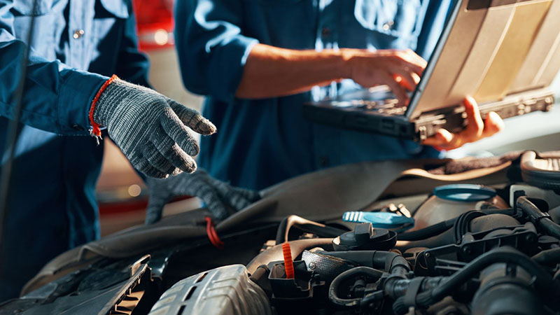 Technician inspecting a car engine for quality control.