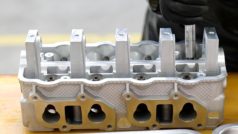 Mecánico instalando componentes en una culata desnuda durante el montaje del motor.