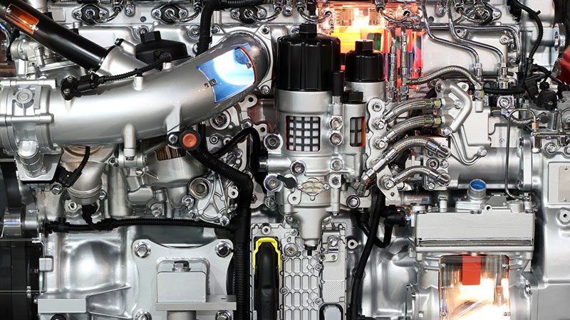Close-up of heavy truck diesel engine showcasing engine block, turbocharger, and fuel injection system components.
