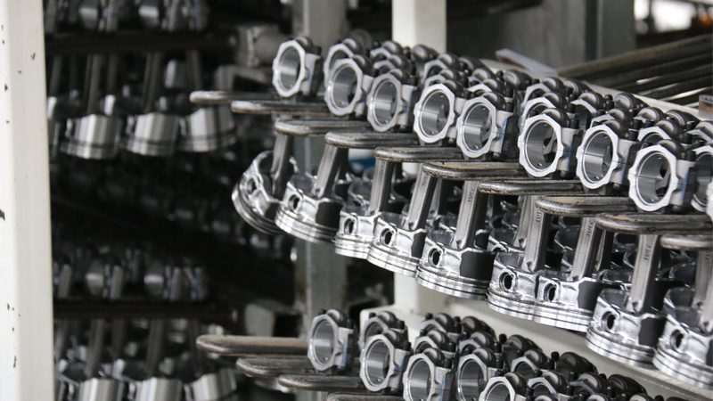 Close-up of multiple pistons displayed in a factory setting, highlighting their design and machining detail.