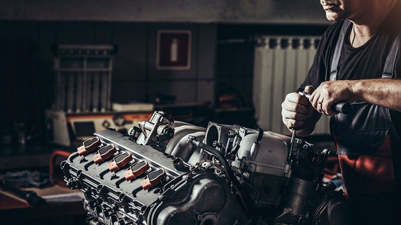Mechanic repairing a V10 engine inside an auto repair shop.