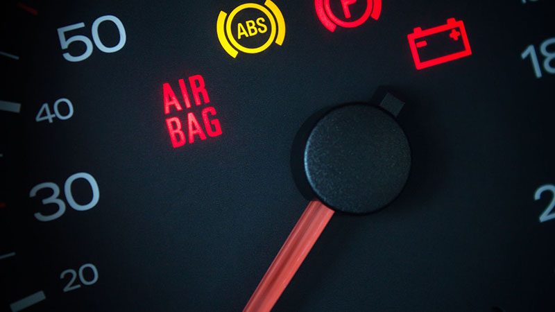 Close-up of car dashboard showing airbag warning light, representing dashboard alerts during limp mode.