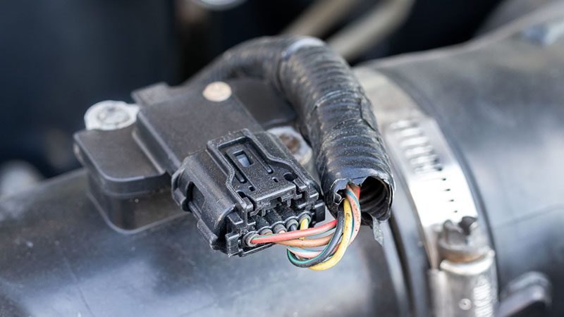 Mass air flow (MAF) sensor under the open hood of a car.