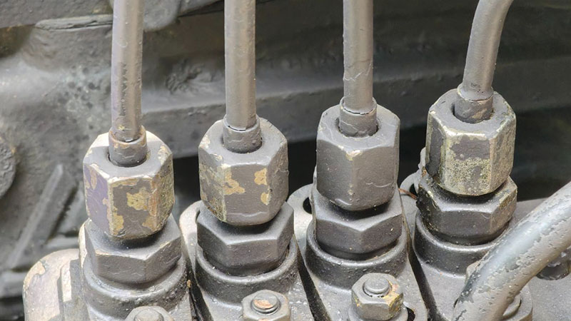 Close-up of fuel injector lines and fittings on an engine with integrated check valve components.