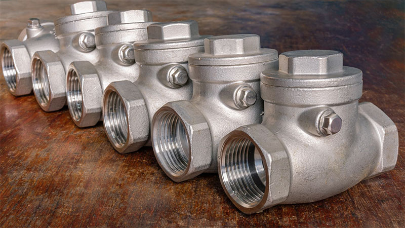 Stainless steel check valve placed on a wooden background.