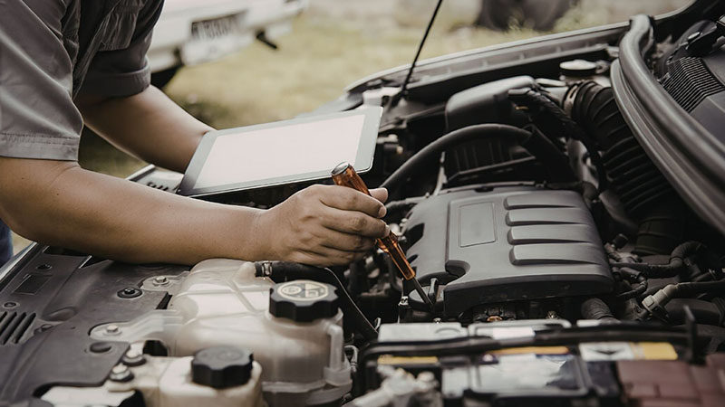 Mechanic inspecting a car engine and checking components.