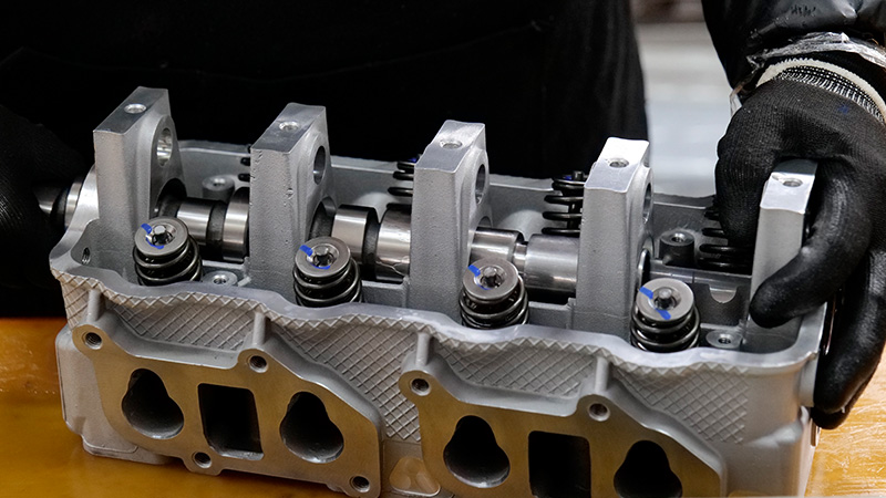 Mechanic assembling a cylinder head on the Woda Auto factory production line.