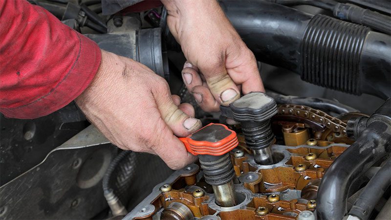 Mechanic installing coil packs into a car engine for optimal ignition performance.