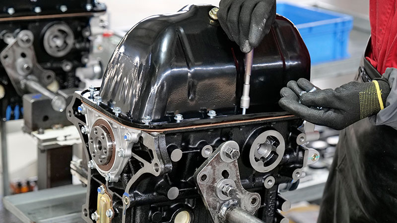 Mechanic assembling an engine on the production line for consistent quality control.