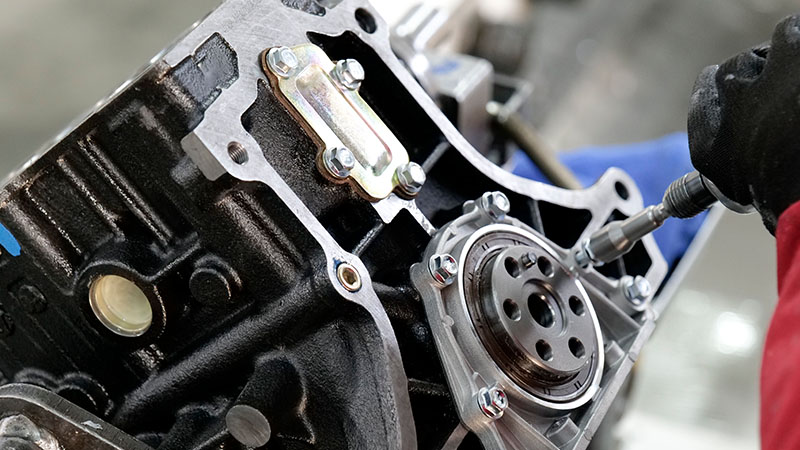 Mechanic working on an engine to check performance and repair quality before installation.