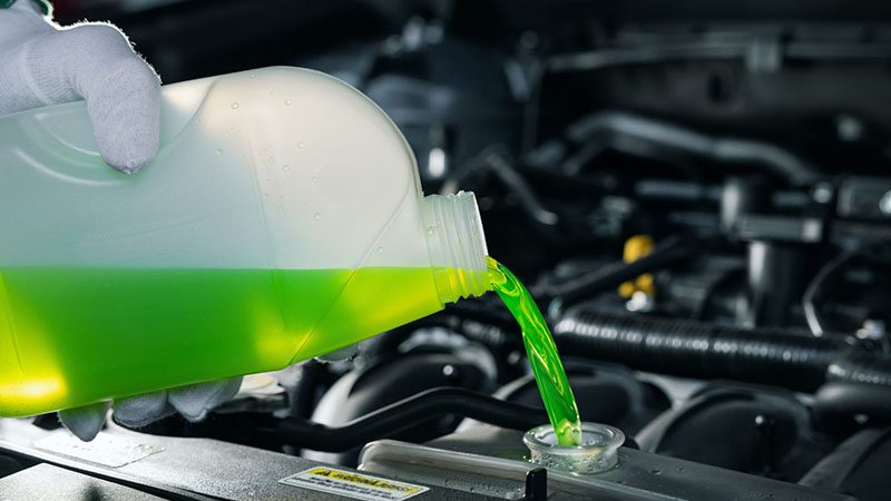 Pouring antifreeze coolant into car engine radiator to prevent overheating