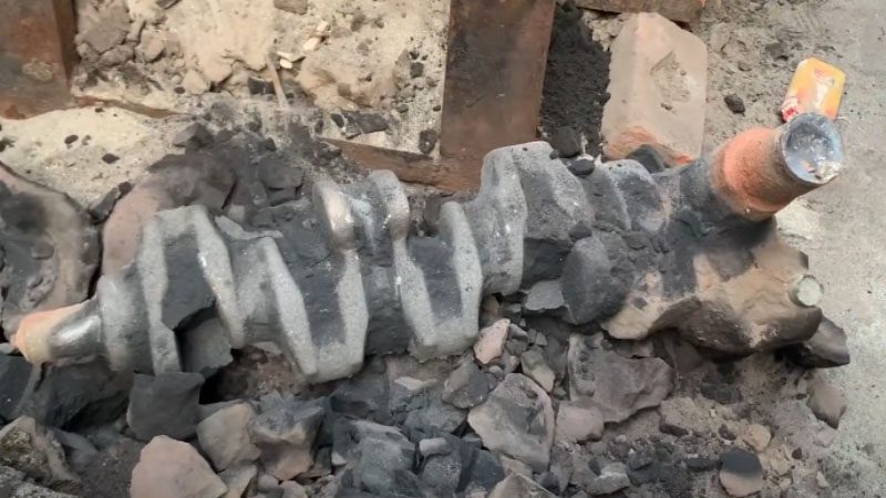 Durch Aufbrechen der Sandform wird die Kurbelwelle freigelegt.