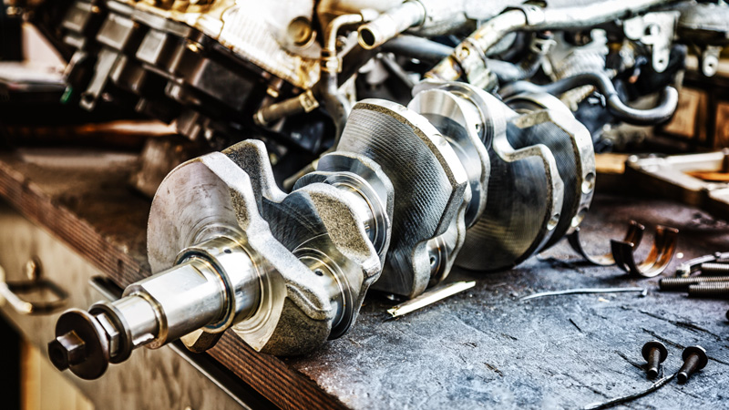 Car engine crankshaft on a workshop table for engine repair and assembly.