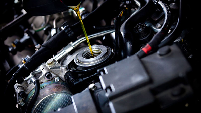 Mechanic performing an oil change on a car engine in a workshop.