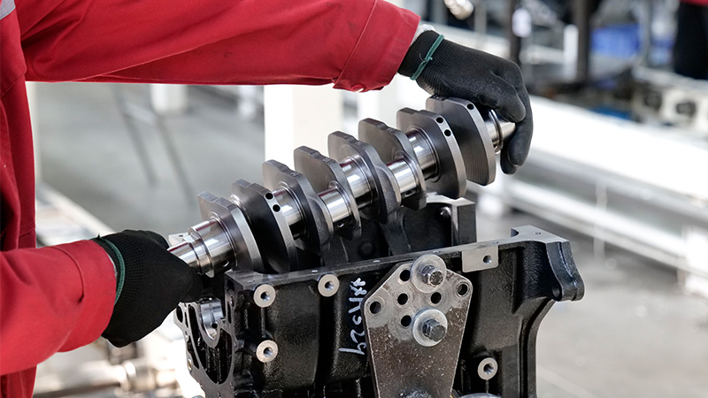 Mecânico instalando um virabrequim em um motor na linha de montagem da fábrica da nossa empresa.