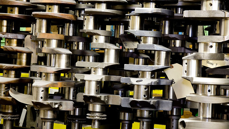 Muscle car engine crankshafts hanging neatly in a machine shop for storage and inspection.