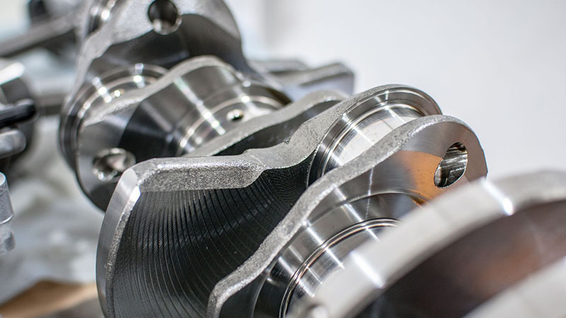 Close-up view of an automotive engine crankshaft showing its journals, counterweights, and precision-machined surfaces.