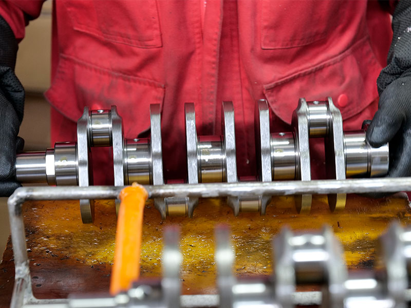 Mechanic inspecting a new crankshaft during quality inspection