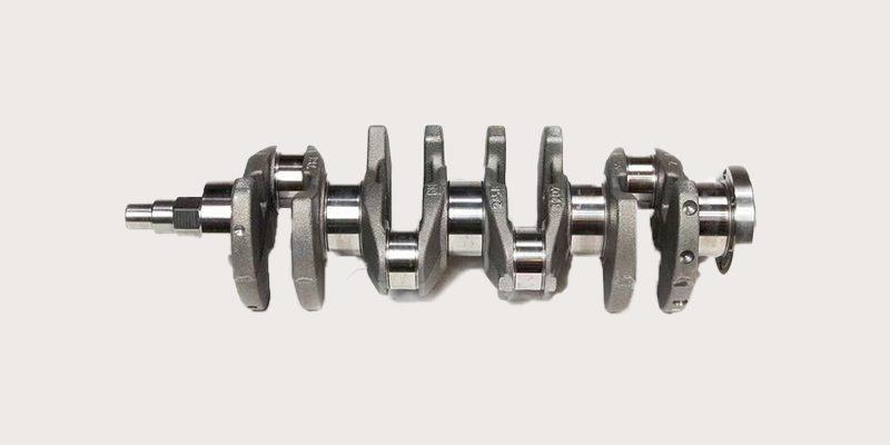 Close-up of a car engine crankshaft, highlighting the main bearings, journals, and counterweights.