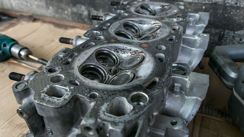 Old cylinder head and engine valve placed on a workshop table.