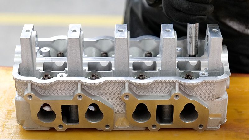 Mecánico ensamblando una culata lista para su instalación en la fábrica de Woda Auto.