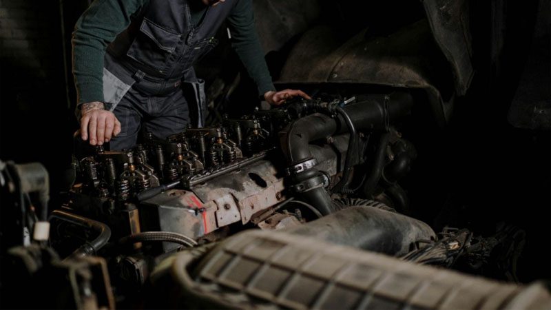 Mecánico inspeccionando las culatas de los cilindros del motor del camión para detectar desgaste y daños.