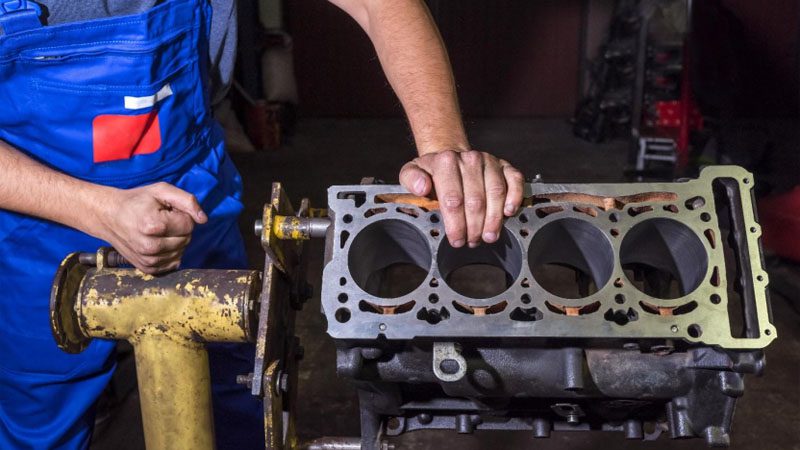 Mechanic inspecting cylinder head condition to diagnose repair or replacement needs.