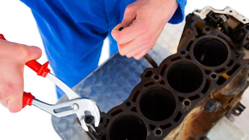 Mecánico reparando una culata de motor.