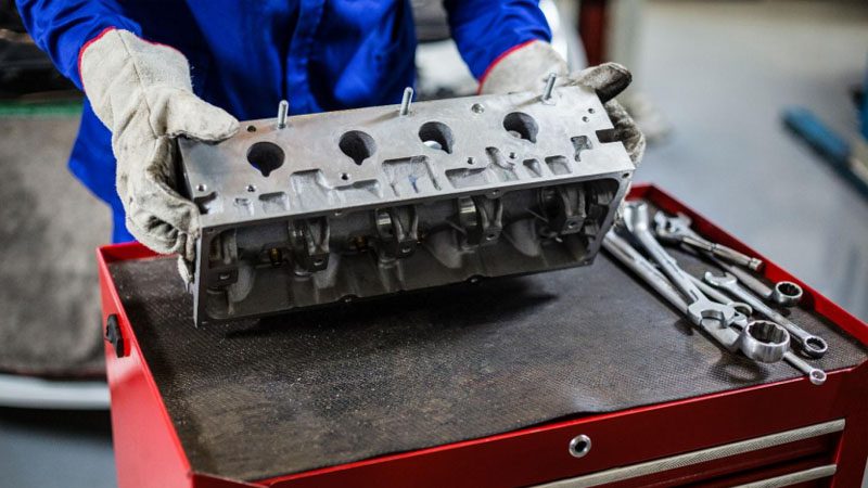 Mecánico reemplazando la culata de un motor de automóvil en un taller de reparación de automóviles.