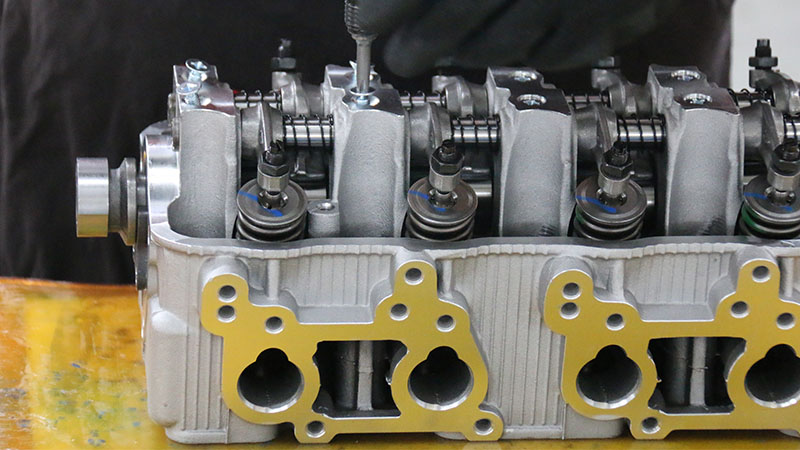 Technician assembling a cylinder head at an automotive factory.